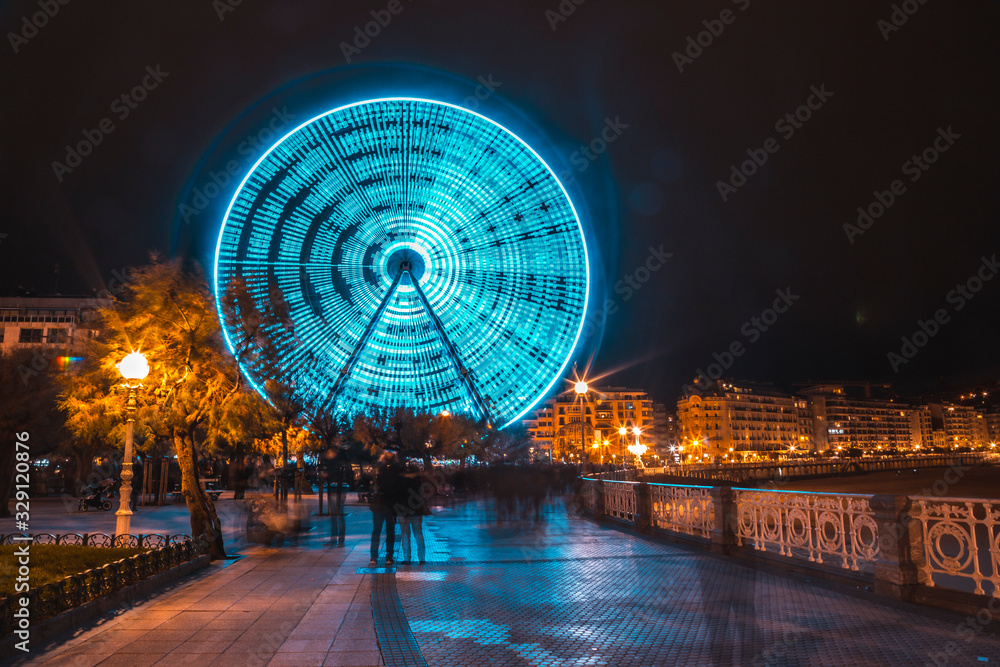 Fototapeta premium Long exposure of the ferris wheel turning san sebastian on top of La Concha at Christmas. Gipuzkoa