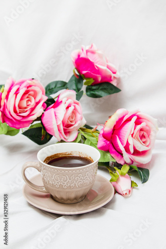Black coffee with pink roses on a white sheet