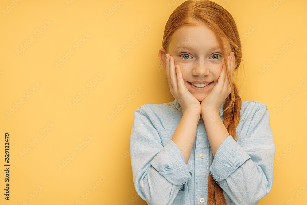 portrait of beautiful positive smiling red haired kid girl over yellow background. caucasian child took up her cheecks and smile at camera, she is in good mood. children, emotions, people concept portrait of beautiful positive smiling red haired kid girl over yellow background. caucasian child took up her cheecks and smile at camera, she is in good mood. children, emotions, people concept