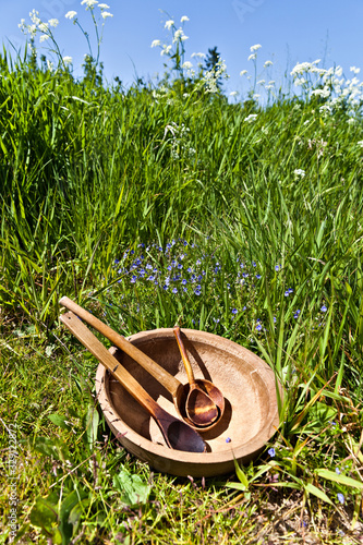 Wooden spoons and wooden bowl on green grass