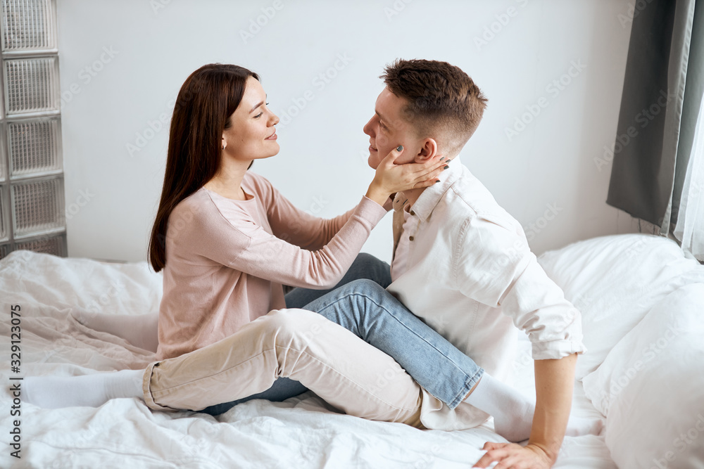 charming girl in beige sweater and jeans flirting with her handsome boyfriend wearing white shirt and pants, full length photo. side view charming girl in beige sweater and jeans flirting with her handsome boyfriend wearing white shirt and pants, full length photo. side view