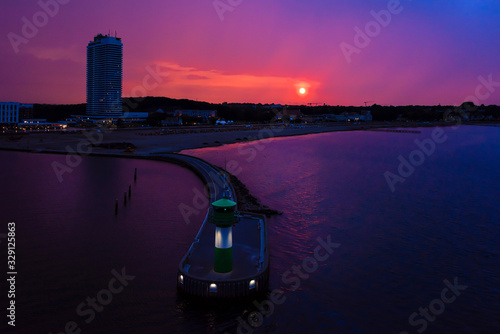 Fototapeta Naklejka Na Ścianę i Meble -  Germany, Travemuende, Hansestadt Luebeck: Colorful panorama aeral view of skyline cityscape with lighthouse, mole, beach, hotel skyscraper and reflections on calm Baltic Sea water - travel tourism