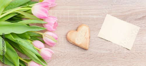 Rosarote Tulpen auf einem hellen Holztisch  mit Holzherz und Postkarte