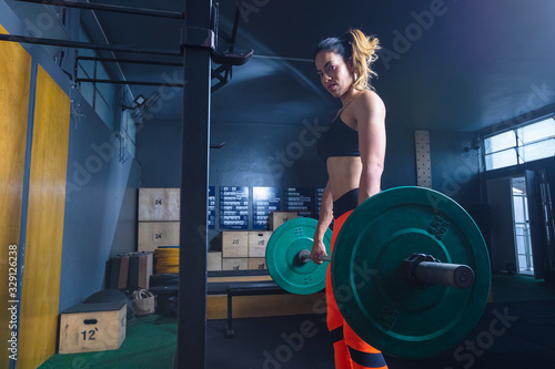 mulher levantando peso na academia estilo crossfit photo