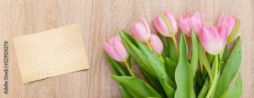 Rosarote Tulpen auf einem hellen Holztisch mit Postkarte
