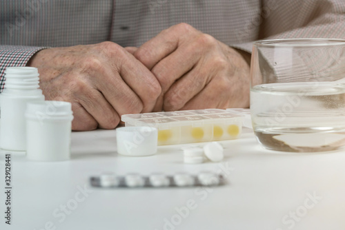 elderly person with drugs and water on white table closeup