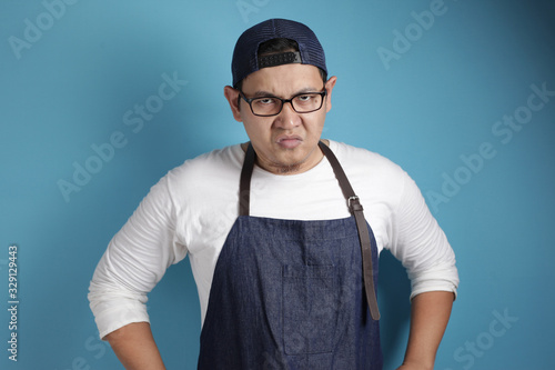 Photo image of funny Asian male chef or waiter shows cynical unhappy angry facial expression photo