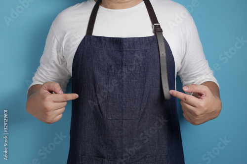 Portrait of male Asian chef or waiter pointing showing his apron, proud confident chef concept