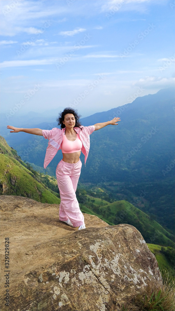 Girl enjoys a mountain view while standing on a cliff Girl enjoys a mountain view while standing on a cliff