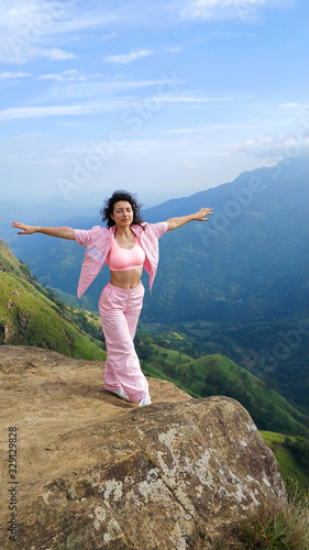 Girl enjoys a mountain view while standing on a cliff