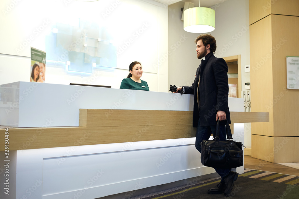 young attractive bearded man cheking in the hotel. side view photo. discounts, sale, guy choosing a room young attractive bearded man cheking in the hotel. side view photo. discounts, sale, guy choosing a room