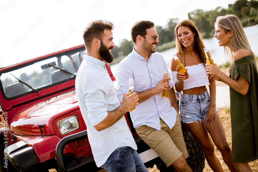 Obraz premium Group of young people drinking and having fun by car outdoor
