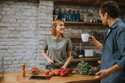 Young  woman cooking while man drinking coffee