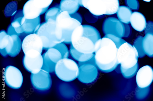 blurred night blue glowing lights on black background. new year and christmas concept. tinted classic blue color trend 2020 year