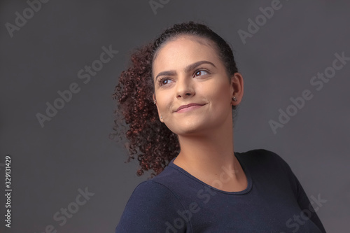 garota jovem empresária no fundo cinza em luz de estúdio, olhar para o lado e para cima com um pequeno sorriso photo