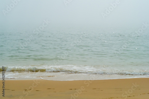 Green Sea Waves on a Yellow Beach in Spain in a Foggy Day