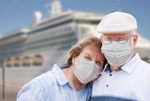 Senior Couple Wearing Face Masks Standing In Front of Passenger Cruise Ship