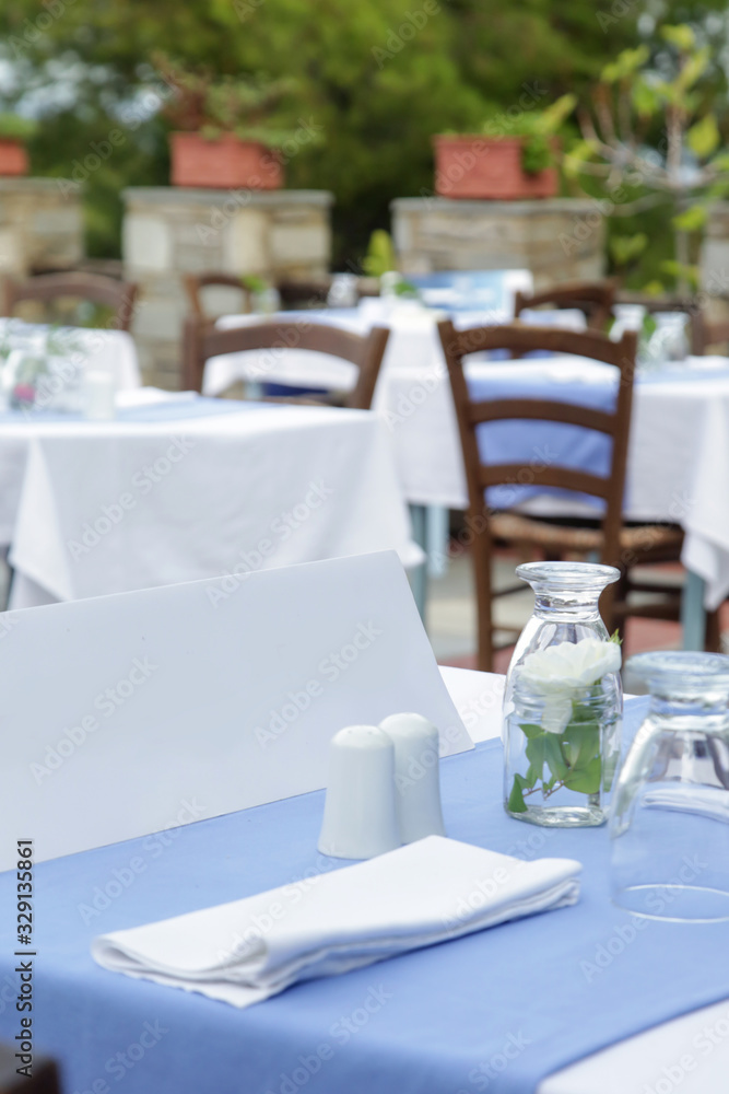 Fototapeta premium The charming retro Mediterranean outdoor restaurant, no people, empty seats and tables before dinner time