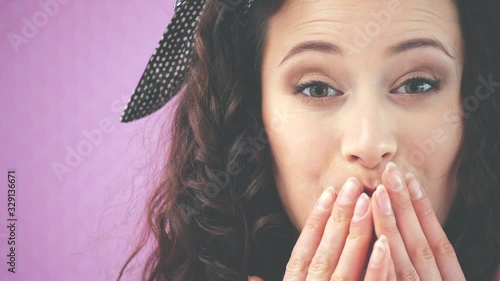 Cropped face of attractive young girl with kinky hair and black headband is looking at the camera, smiling, giving an airkiss. photo