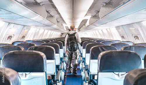 Inside view of commercial airplane with lonely man traveler - Emergency travel concept about flight cancellation - Aerospace industry crisis with empty plane on bright azure filter photo