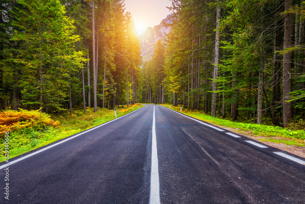 Fototapeta premium Mountain road. Landscape with rocks, sunny sky with clouds and beautiful asphalt road in the evening in summer. Vintage toning. Travel background. Highway in mountains.