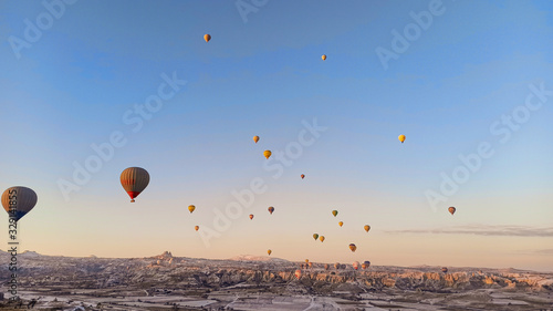 Colorful hot air balloons flying over the valley with fairy chimneys in winter season. Lots of Hot air balloons at the sunrise sky landscape in Cappadocia, Turkey © Alohadunya