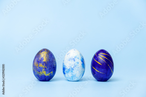 Three easter trendy colored classic blue, white and golden decorated eggs on blue. Happy Easter card with copy space for text. Minimal style