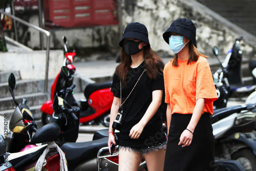 Two Chinese women are walking down the street with gauze masks on their faces. The threat of a coronavirus epidemic in China. Covid-19