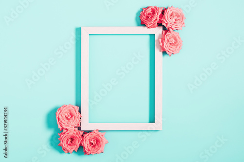 Beautiful flowers composition. Blank frame for text, pink rose flowers on pastel blue background. Womens day, mothers day, concept, design. Flat lay, top view, copy space