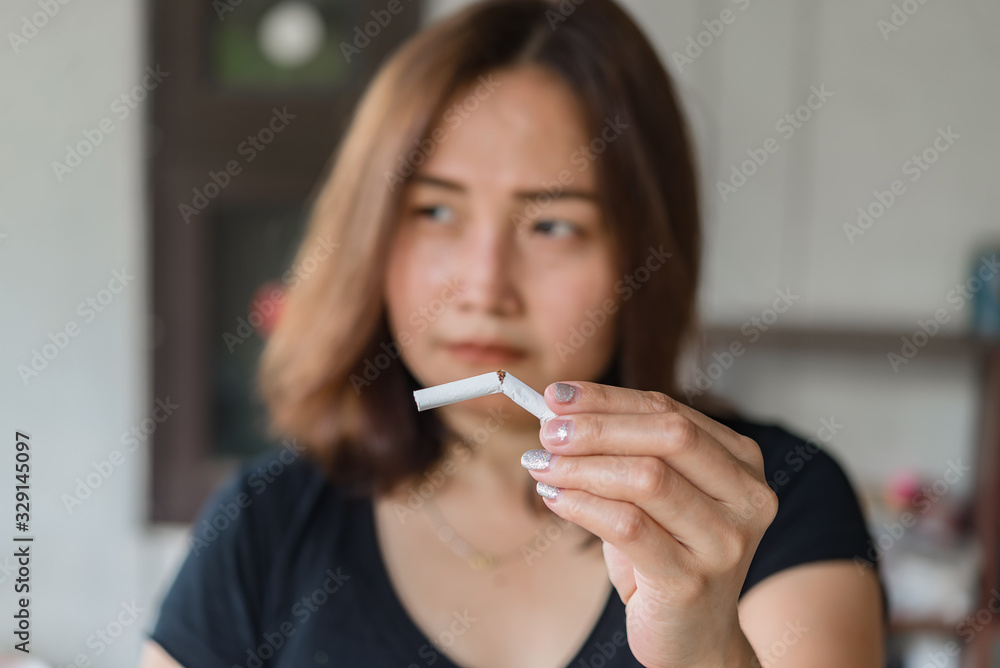Asian woman hand crushing cigarette.Quitting from addiction concept,No tobacco day,No smoking concept Asian woman hand crushing cigarette.Quitting from addiction concept,No tobacco day,No smoking concept