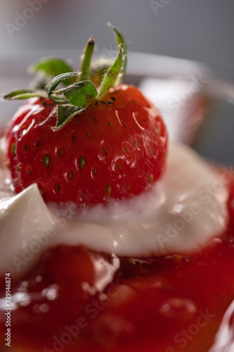 Cream dessert with fresh strawberries and strawberry jam in a glass bowl on a dark background