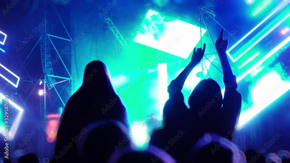 The crowd watches a concert, sings, jumps. Strobing stage lights. Happy people are watching an amazing concert. People make photos and videos at the festival. World tour of popular musicians. The crowd watches a concert, sings, jumps. Strobing stage lights. Happy people are watching an amazing concert. People make photos and videos at the festival. World tour of popular musicians.
