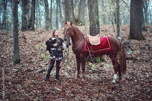 Tableau sur toile Warrior woman with her brown horse into the woods - Beautiful scandinavian vikin