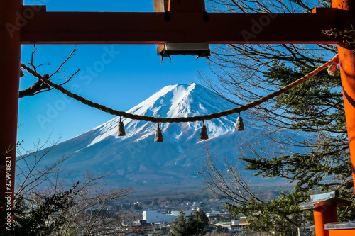 Distant view on Mt Fuji, framed in between orange Torri gate, decorated with bells,  on a clear, wintery day. The top parts of the volcano are covered with a layer of snow. Holly mountain photo