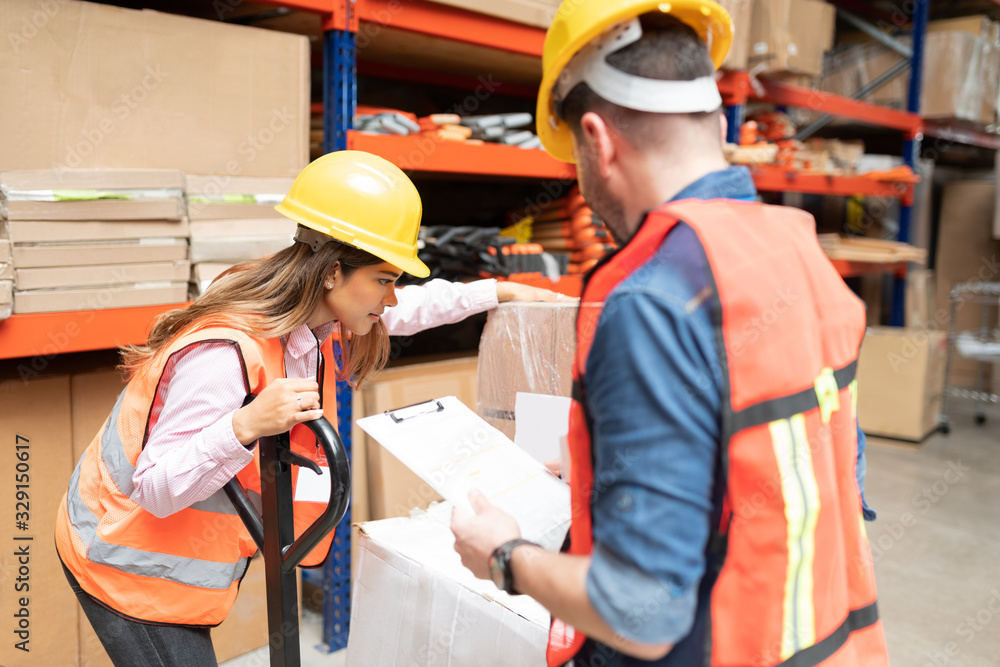 Male And Female Workers Checking Inventory At Warehouse Male And Female Workers Checking Inventory At Warehouse