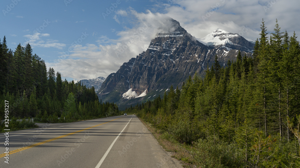 Fototapeta premium Road with snowcapped mountain range in the background, Icefield Parkway, Alberta, Canada