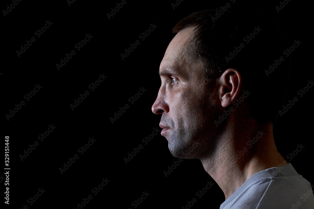 Serious man in a t-shirt on a dark background Serious man in a t-shirt on a dark background