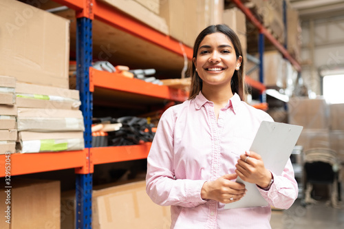 Happy Young Latin Worker With List Working At Factory photo