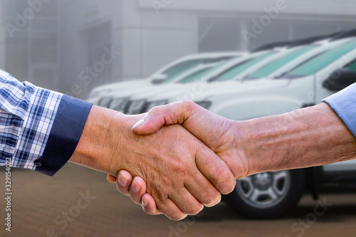 Foto Businessmen sign a deal to sell a car with a handshake