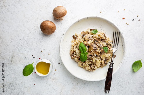 Risotto with mushrooms in a white plate over white background, top view