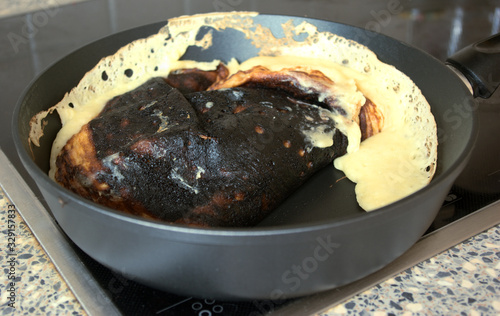 Cooking fail. Burned omelet in pan close-up. Amateur culinary. Chores.