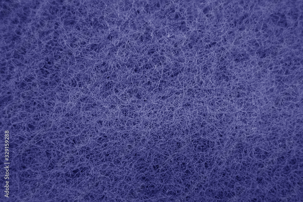 Cleaning sponge rubbing surface close up with blue effect in blue tone.