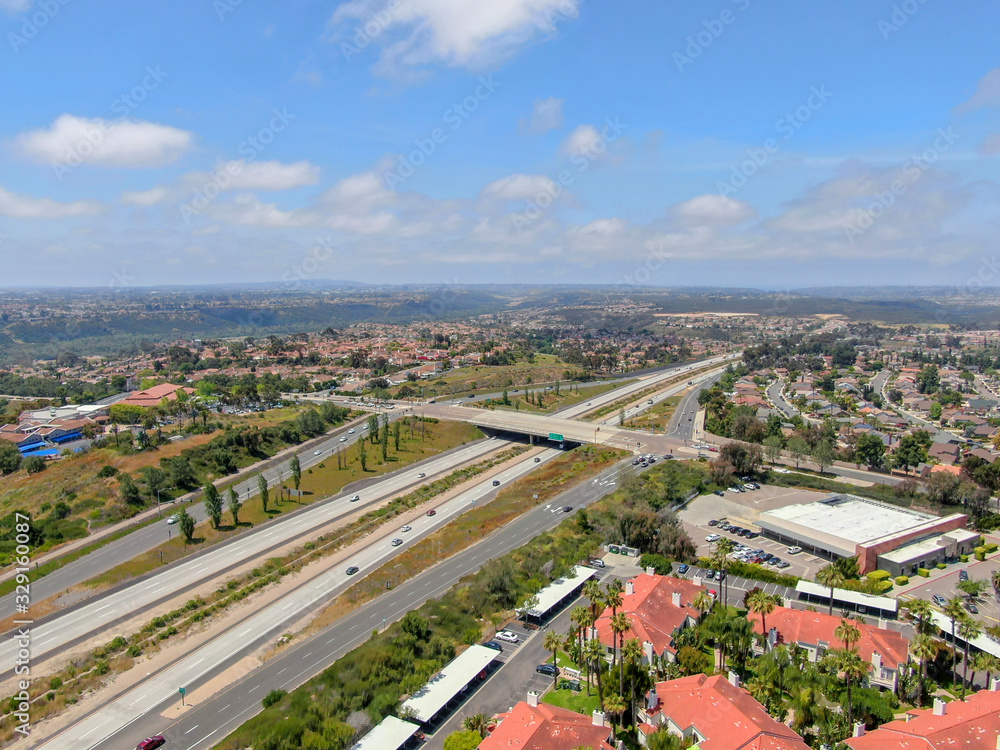 Aerial view of highway surrounded by villa in suburb. Intersection city transport road with vehicle movement. California, USA.