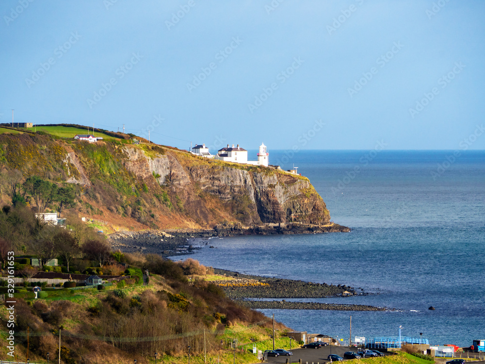 Blackhead Lighthouse in Whitehead village on a steep cliff on the Atlantic coast in County Antrim, Northern Ireland, UK