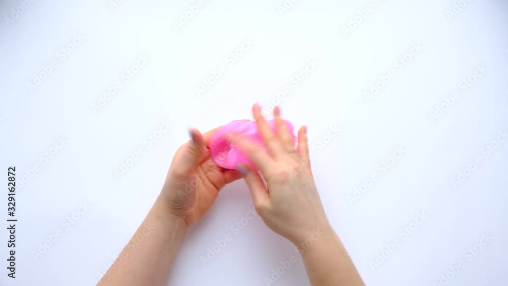 Woman hands playing with pink slime on white background. Trendy liquid toy. Top view. 4k footage. Woman hands playing with pink slime on white background. Trendy liquid toy. Top view. 4k footage.
