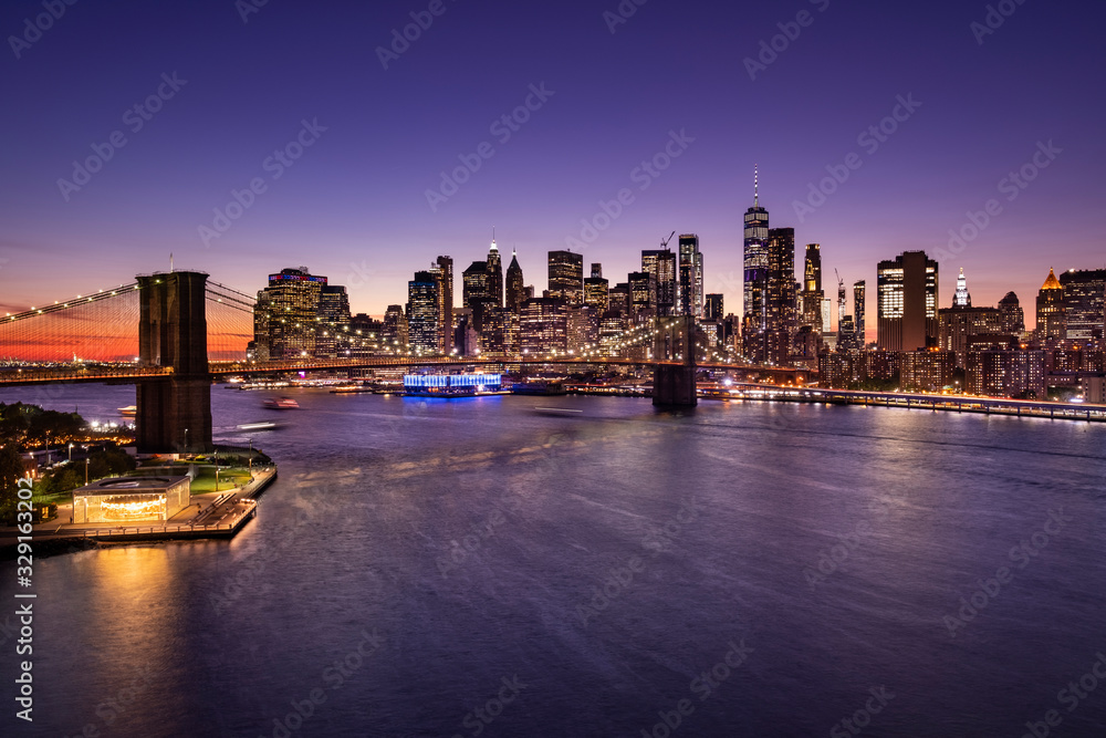 Obraz premium Brooklyn Bridge over the East River and the Manhattan downtown city skyline at night in New York USA