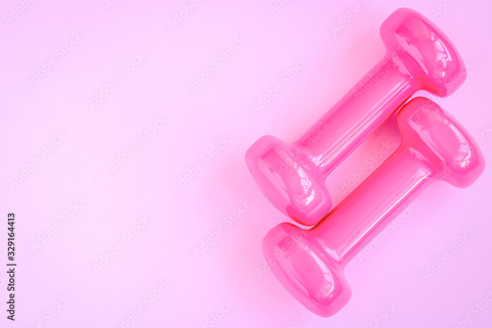 Closeup view of the pair of pink dumbbells on a colourful background. Copy space. Health lifestyle concept. Closeup view of the pair of pink dumbbells on a colourful background. Copy space. Health lifestyle concept.
