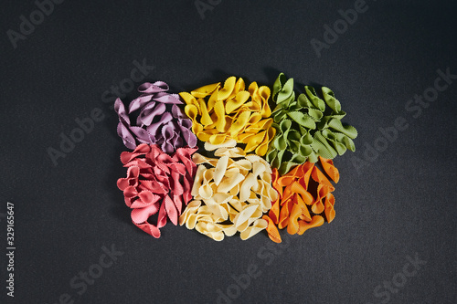 Uncooked groups of six color pasta on a black background