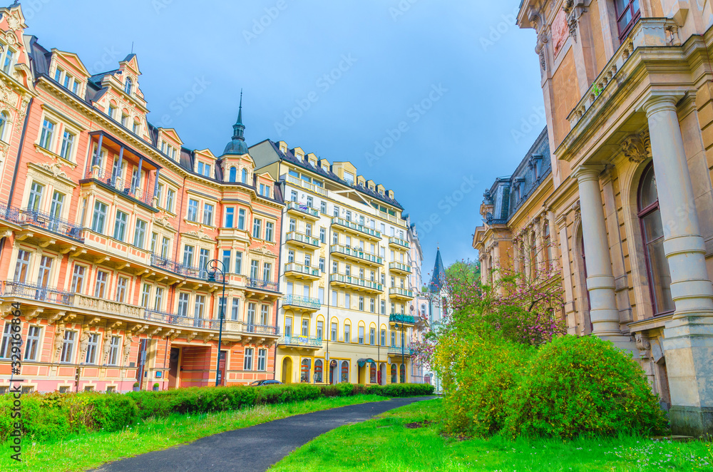 Karlovy Vary (Carlsbad) historical city centre with colorful beautiful traditional buildings, Kaiserbad Spa Imperial Bath or Lazne I, lawn with green grass and bushes, West Bohemia, Czech Republic