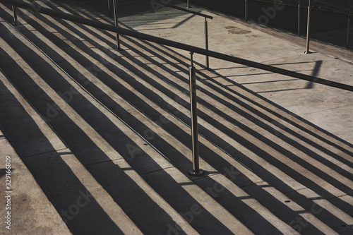 Escalera de cemento con barandas de acero. Sombras proyectadas en los escalones.